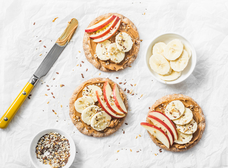 Peanut butter, apple, banana, flax and chia seed  crackers toast on a light background, top viewの写真素材