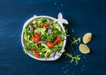 Smoked salmon, avocado, arugula, red onion salad. Healthy snacking on blue background, top viewの写真素材