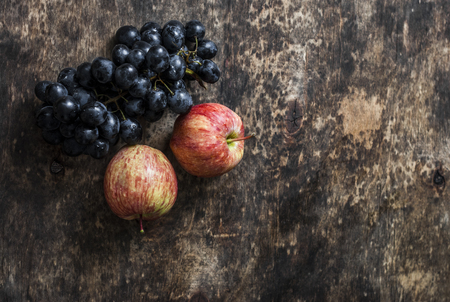 Fresh ripe autumn fruit apples and grapes on rustic wooden background, top view. Free space for textの写真素材