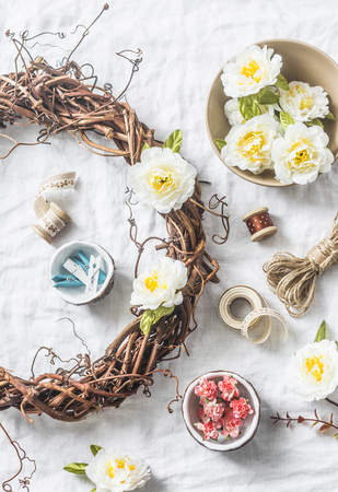 Homemade wreath with flowers and accessories for crafts creativity on a light background, top view. Flat layの写真素材