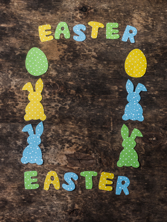 Easter background. Empty frame composition with paper handmade rabbits on wooden rustic background, top view. Easter decorations. Free space for text, flat layの写真素材