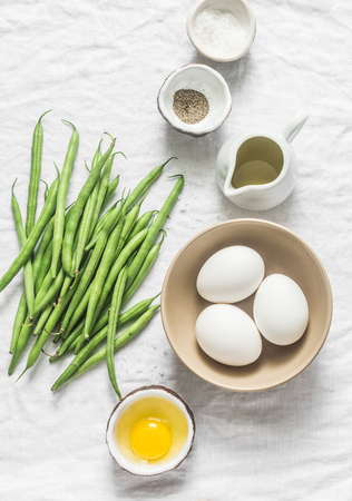 Raw ingredients - eggs, green beans, olive oil, spices on a white background, top view. Flat layの写真素材
