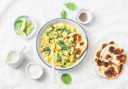 Chickpeas, spinach, potato curry plate and naan flatbread on white background, top view. Indian healthy vegetarian foodの写真素材
