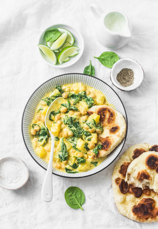 Vegetarian chickpea, spinach, potato curry plate and naan flatbread on white background, top view. Indian healthy foodの写真素材