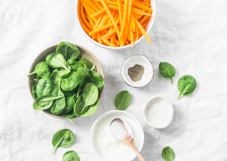 Healthy food ingredients for cooking - slices of pumpkin, spinach, cream and spices on white background, top viewの写真素材