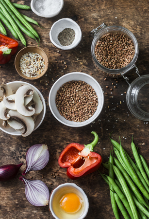 Flat lay healthy vegetarian food ingredients for lunch on a wooden background, top view. Buckwheat, green beans, sweet peppers, red onion, mushrooms, egg - clean eating vegetarian food conceptの写真素材