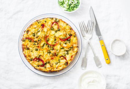 Potatoes and vegetables tortilla on a light background, top view. Potatoes, green beans, bell peppers, green peas, cheese, eggs casserole - a delicious breakfast or snackの写真素材