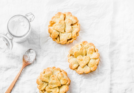 Flat lay crispy shortcrust pastry  apple tartlets on light background, top view. Valentine's day bakingの写真素材
