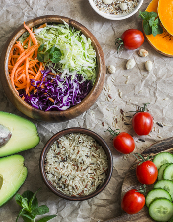 Healthy vegetarian food set background. Cabbage salad, avocado, tomatoes, cucumbers, pumpkin, wild rice on a paper background, top view. Flat layの写真素材