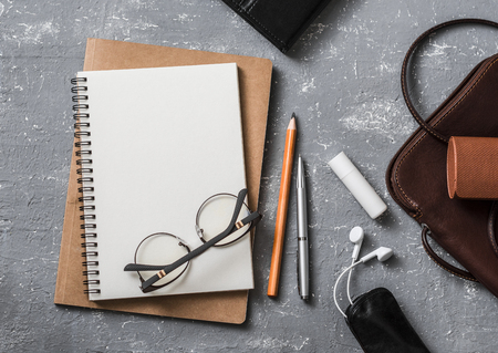 Flat lay female office desk with notepad, tablet, leather bag, glasses, earphones,lipstick. On a gray background, top viewの写真素材