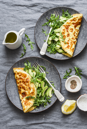 Omelette with cream cheese, arugula and avocado salad on a grey background, top view.  Healthy breakfast or diet lunchの写真素材