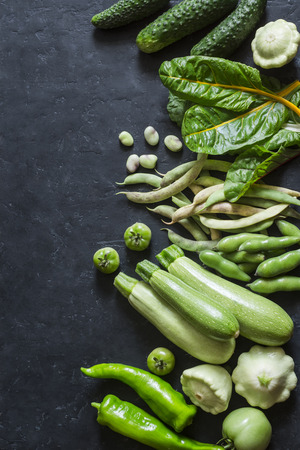 Freshness  green garden vegetables food background. Zucchini, peppers, green beans, squashes, cucumbers, chard  on dark background, top view. Organic detox products. Flat layの写真素材
