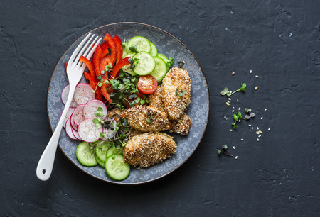 Sesame crust baked chicken breast and fresh vegetables. Baked chicken and tomatoes, cucumbers, peppers, radishes, micro greens salad, top view. Flat lay, free spaceの写真素材