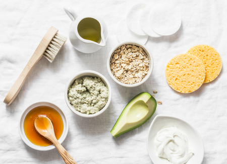 Ingredients for moisturizing, nourishing, anti-aging wrinkle face mask - avocado, olive oil, oatmeal, natural yogurt on light background, top view. Homemade beauty products conceptの写真素材