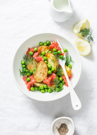Young baked potato, smoked salmon, green peas and dill salad on light background, top viewの写真素材