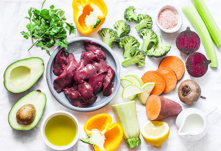 Ingredients for lunch - chicken liver, sweet potatoes, broccoli cabbage, bell peppers, beets, beans, spices, olive oil, zucchini, avocado, celery. Healthy, nutritious food set on white background, top view. Flat layの写真素材