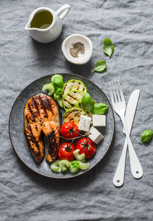 Grilled salmon, zucchini, baked cherry tomatoes and silky tofu - healthy balanced meal on grey background, top viewの写真素材