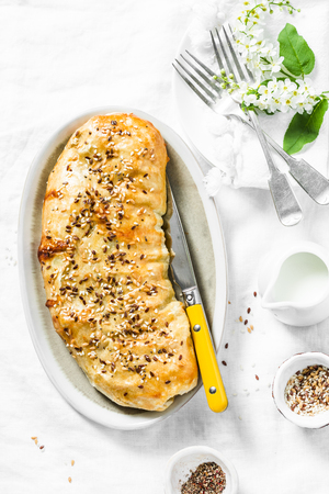 Puff pastry savoury strudel with cabbage, broccoli and mozzarella cheese served on a white table, top view. Flat layの写真素材