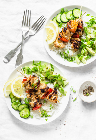Grilled chili honey lime chicken skewers with rice and avocado salsa on light background, top view. Flat layの写真素材
