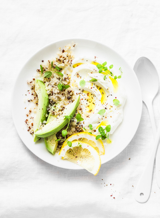 Greek yogurt with avocado, quinoa, greens, spice bowl on white background, top view. Healthy appetizerの写真素材