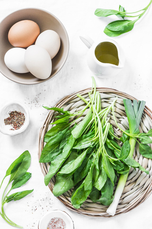Ingredients for green shakshuka - fresh spinach, garlic, ramson and organic farm eggs on white background, top view. Healthy  food ingredientsの写真素材