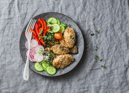 Baked chicken breast with sesame and fresh vegetables salad - healthy diet lunch on grey background, top viewの写真素材