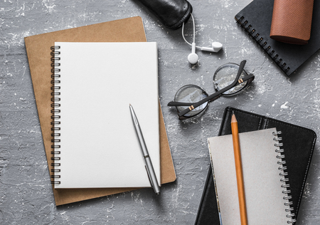 Flat lay office workplace. Business or education accessories - blank notepad glasses, pens, pencils, headphones on grey background, top view. Space for textの写真素材