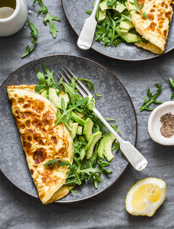 Omelette with avocado arugula salad - healthy snack or breakfast on a grey background, top viewの写真素材