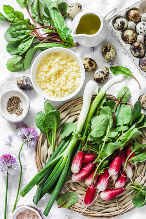 Healthy food ingredients - fresh spinach, chard, radish, couscous, quail eggs, olive oil on a light background, top view. Salad ingredientsの写真素材