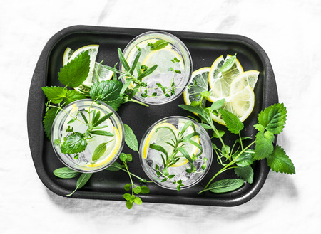 Garden herbs lemonade. Infused water with lemon, rosemary, thyme, sage and mint on light background, top view. Summer cool drinkの写真素材
