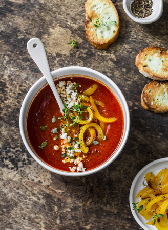Vegetarian tomato soup with baked yellow sweet pepper on wooden background, top viewの写真素材