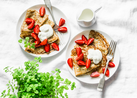 Breakfast, dessert table - crepes with strawberries and cream on a white background, top view. Flat layの写真素材