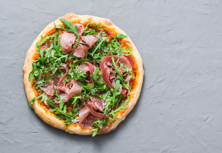 Prosciutto homemade pizza on grey background, top view. Delicious appetizers, snack, tapas in mediterranean style. Free spaceの写真素材