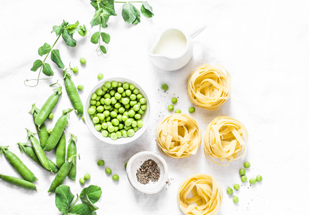 Mediterranean style healthy food ingredients for cooking lunch - fettuccine pasta, fresh green peas, cream, spices on a light background, top view. Flat layの写真素材