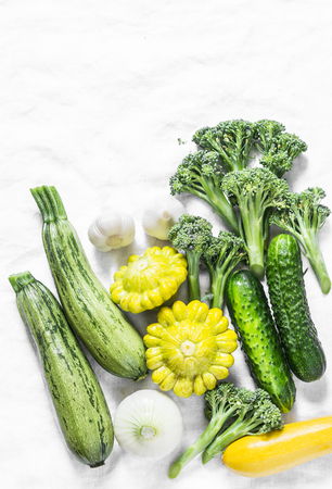 Broccoli, zucchini, squash, garlic, cucumbers - fresh organic vegetables on a light background, top view. Flat lay, copy spaceの写真素材
