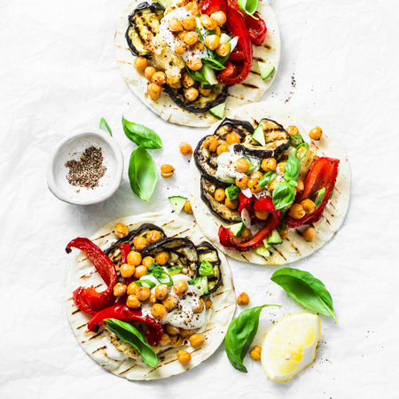 Tortillas with spicy chickpeas, grilled eggplant, cauliflower and pepper on a light background, top view. Delicious vegetarian snack, tapas, appetizers. Flat layの写真素材