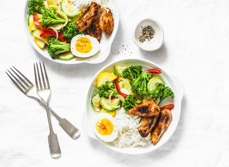 Lunch served - stewed vegetables, rice, boiled egg and teriyaki chicken on light background, top viewの写真素材