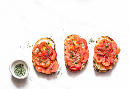 Heirloom tomatoes, feta cheese, oregano bruschetta on a light background, top view. Delicious appetizers, tapas, snackの写真素材