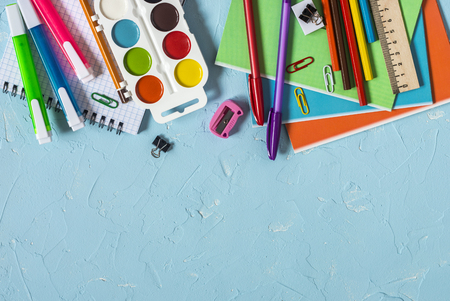 Back to school. School accessories - notebooks, pens, pencils, paint on a blue background, top view. Education concept. Flat lay, copy spaceの写真素材