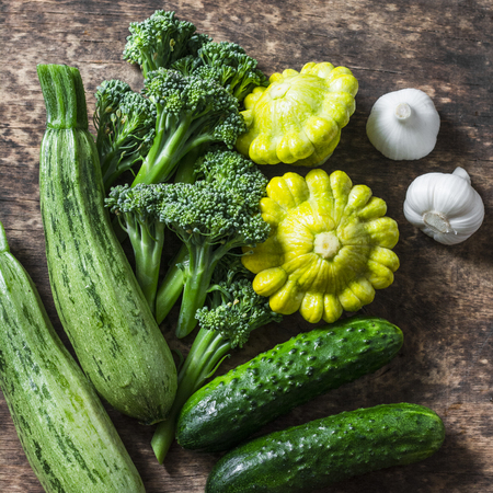 Broccoli, zucchini, squash, garlic, cucumbers - fresh organic vegetables on a wooden background, top view. Flat layの写真素材