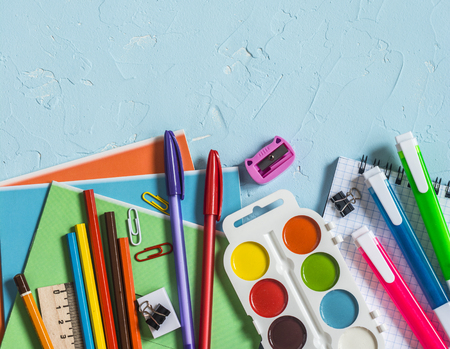 Back to school. School accessories - notebooks, pens, pencils, paint on a blue background, top view. Education concept. Flat lay, copy spaceの写真素材