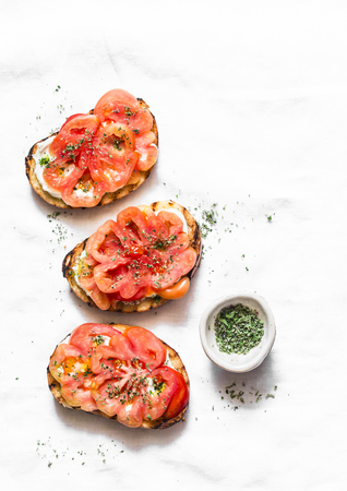 Heirloom tomatoes, feta cheese, oregano bruschetta on a light background, top view. Delicious appetizers, tapas, snackの写真素材