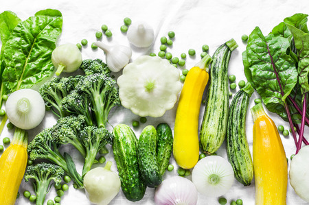 Fresh organic vegetables - zucchini, squash, cucumbers, broccoli, onions, garlic, chard, green peas on a light background, top view. Healthy lifestyle diet vegetarian food concept. Flat layの写真素材