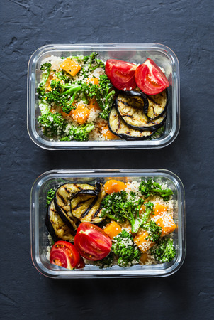 Vegetarian lunch box. Broccoli, pumpkin, couscous salad, grilled eggplant and tomatoes. Healthy diet home food concept. Office food. On dark background, copy spaceの写真素材