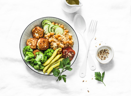 Healthy balanced buddha bowl lunch - spicy couscous with chickpeas, broccoli, green beans and turkey meatballs on light background, top view. Flat layの写真素材