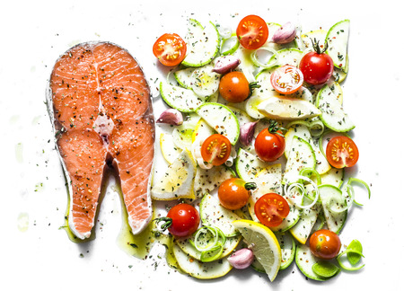 Ingredients for cooking  healthy lunch - salmon and vegetables. Red fish, zucchini, squash, cherry tomatoes, leek, wild rice, spices on a light background, top view. Flat layの写真素材