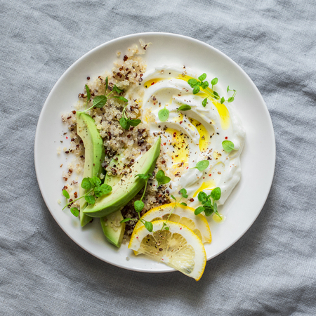 Greek yogurt with avocado, quinoa, greens, spice bowl on grey background, top view. Healthy appetizer, tapas, snackの写真素材