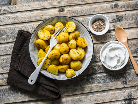 Baked turmeric potatoes on a wooden background, top view. Delicious vegetarian lunch, snackの写真素材