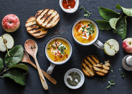 Roasted butternut squash and apples paleo diet vegetarian soup on dark background, top view. Flat layの写真素材