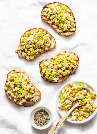 Corn and goat cheese grilled bruschetta on a light background, top view. Delicious snack or appetizersの写真素材